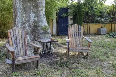 two wooden chairs and a table in front of a tree at Le Mas des Anges in Cabannes