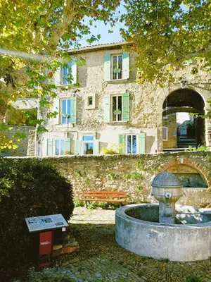 a stone building with a fountain in front of a building at L'appartement de l'Arche in Châteauneuf-de-Gadagne