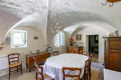 a dining room with a white table and chairs at le mas du lavoir in Gordes