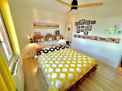 a bedroom with a yellow and white bed and a ceiling fan at Villa entière au calme avec piscine partagée et jardin in Pertuis