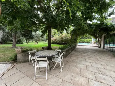 a patio with a table and chairs under a tree at The Garden View in Le Thor