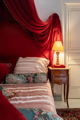 a bedroom with a red curtain over a bed and a lamp at Appartement de luxe : Le Petit Trianon au coeur d'Aix-en-Provence in Aix-en-Provence