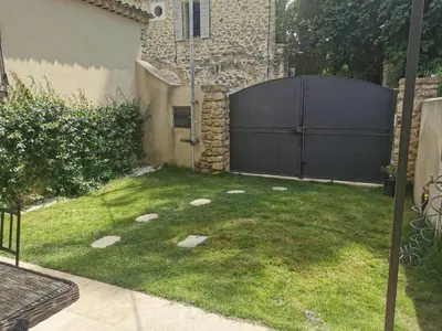 a backyard with a black gate and a grass yard at Maison de la bonne fontaine. in Lauris