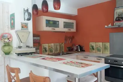a kitchen with a white counter and orange walls at Au goût du miel. Luberon-Provence. in Maubec