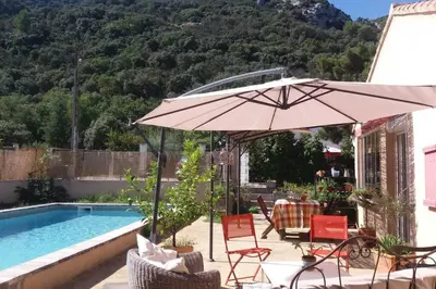 a patio with an umbrella and chairs next to a pool at Au goût du miel. Luberon-Provence. in Maubec