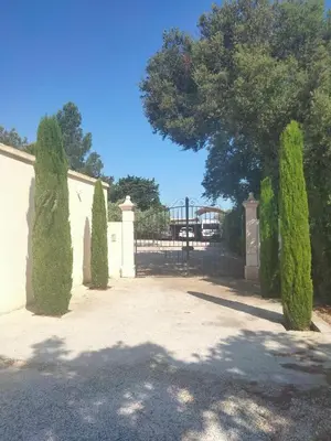 a gate to a house with hedges and a tree at Chambre d'hôte suite Tournesol 