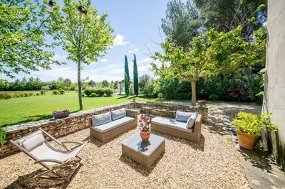 a patio with two couches and a table and chairs at Villa des Alpilles in Eygalières