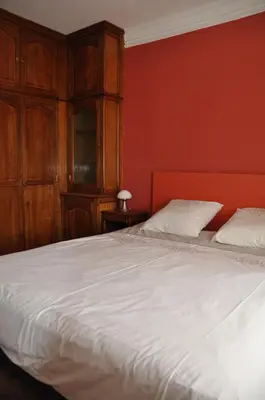 a bedroom with a white bed and a red wall at Maison de caractère au coeur de la Provence in Mallemort