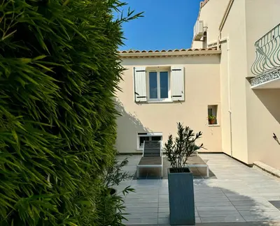 a building with a large green hedge next to a courtyard at Les 2 Oliviers in Caromb