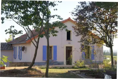 a white house with blue shutters and a tree at Masmazan in Mazan