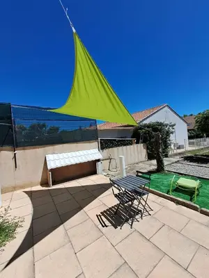 a green umbrella on a patio with a table and chairs at La Petite Maison des Boettes in Carpentras