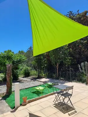 a green umbrella over a table and a green pond at La Petite Maison des Boettes in Carpentras
