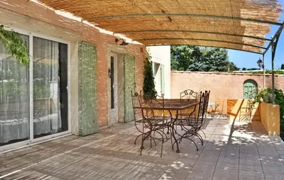 a patio with a table and chairs on a porch at La Villa Des Songes in Pernes-les-Fontaines