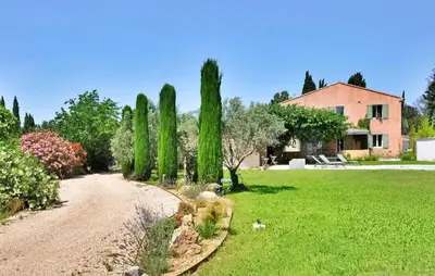 a garden with cypress trees and a house at La Villa Des Songes in Pernes-les-Fontaines