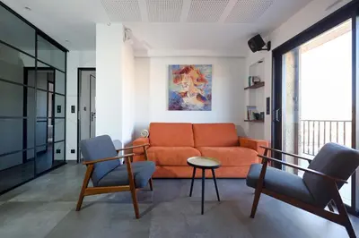 a living room with an orange couch and two chairs at Aix Rooftop Appartement T2 Luxe 5 étoiles - hypercentre Rotonde - Terrasse - Vue - Parking in Aix-en-Provence