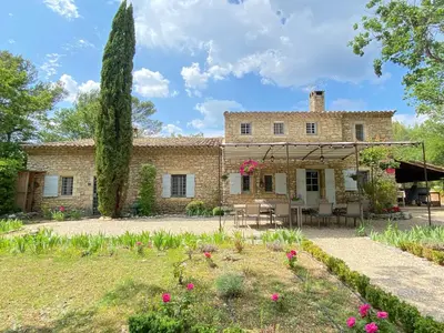 an exterior view of a stone house with a patio at Mas de Veroncle, piscine et quiétude à Gordes in Gordes
