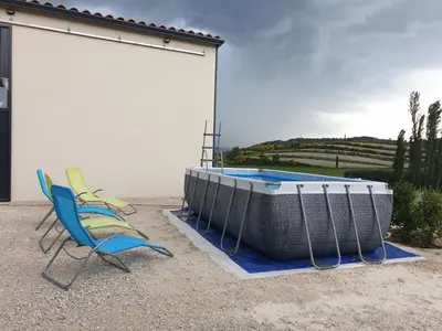 a pair of chairs and a swimming pool next to a building at Appartement neuf Bédoin - Les Cinglés du Mont Ventoux in Mormoiron