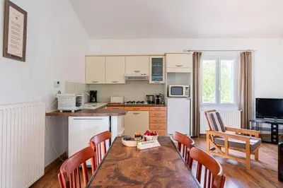 a kitchen with a wooden table with chairs and a tableasteryasteryasteryasteryastery at Charmant T2 2/4 Personnes in Pernes-les-Fontaines