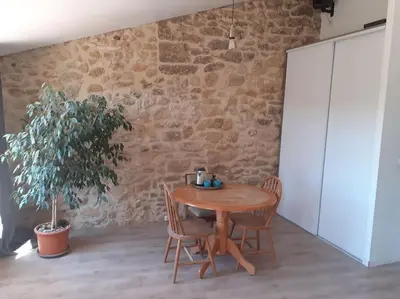 a table and chairs in a room with a stone wall at Maison restaurée à l'ancienne avec terrasse in Jouques