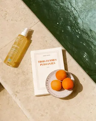 a bowl of oranges and a book and a bottle of liquid at Le Clos de Gordes in Gordes