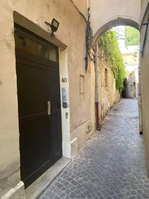 an alley with a black door on the side of a building at Escapades L'Isloises au cœur de L'Isle-sur-la-Sorgue. in LʼIsle-sur-la-Sorgue