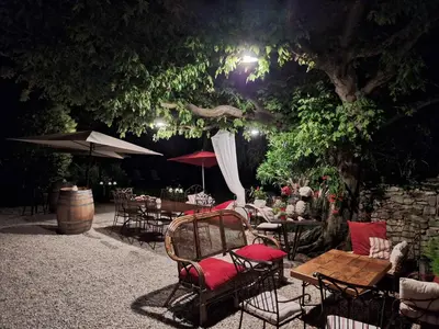 a group of tables and chairs under a tree at night at Cherche Midi in Noves