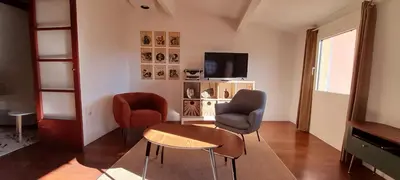 a living room with two chairs and a table and a tv at L'atelier au coeur du village in Roussillon
