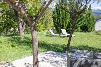 a white lounge chair in a field with trees at L Orchidée in Mormoiron