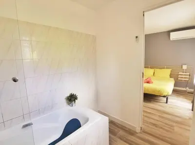a white bathroom with a tub and a bedroom at Les quatre loges - joli t2 jardinet et parking *3 in Aix-en-Provence