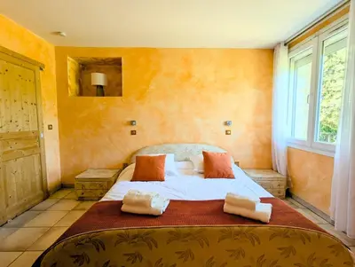 a bedroom with a large bed with orange walls at L'Escargolette - Incroyable maison de vacances 4 étoiles in Carpentras