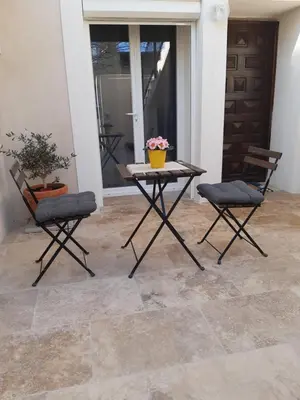 a patio with two chairs and a table with flowers on it at Le gîte d'églantine in Eyguières