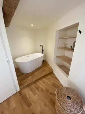 a bathroom with a white bath tub on a wooden floor at La Maison Jaune, une expérience inoubliable in Villes-sur-Auzon