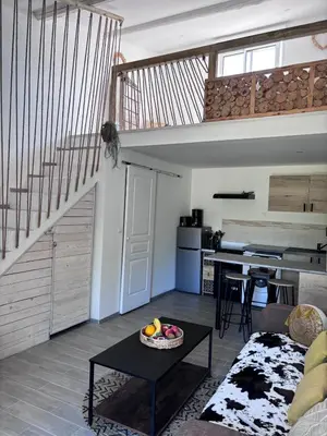 a living room with a staircase and a table at Appart Hôtel - Nature et Spa in Aurons