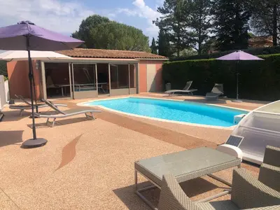 a pool with chairs and umbrellas next to a house at VILLA AVEC PISCINE in Roussillon