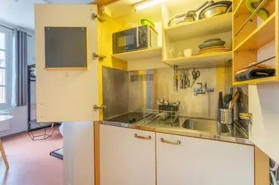 a kitchen with yellow walls and white cabinets at Studio calme et lumineux in Aix-en-Provence