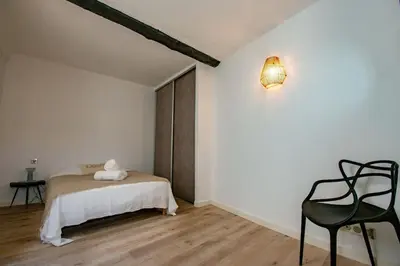 a bedroom with a bed and a black chair at Moderne et lumineux - clim - wifi in Aix-en-Provence
