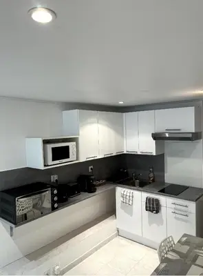 a kitchen with white cabinets and a microwave at T3 avec jardin et piscine privée in Velaux