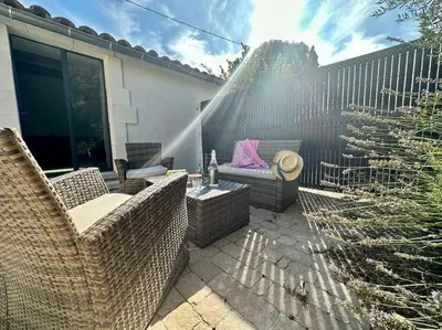 a patio with wicker chairs and a bench and a fence at Ô Sorgue in LʼIsle-sur-la-Sorgue