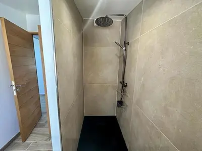 a bathroom with a shower with a black floor at Ô Sorgue in LʼIsle-sur-la-Sorgue