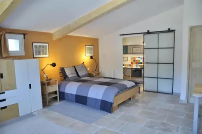 a bedroom with a king sized bed and a kitchen at Gite Hardy in Velleron