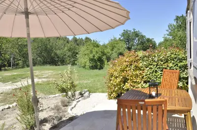 an umbrella and a wooden table and chairs on a patio at Gite Hardy in Velleron