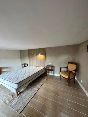 a bedroom with a large bed and a chair at Appartement centre village in Roussillon