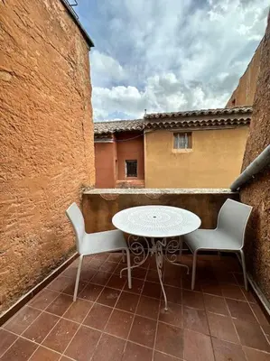 a patio with a table and two chairs on a balcony at Appartement centre village in Roussillon