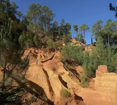 a person walking on a rocky hill with trees at Appartement centre village in Roussillon