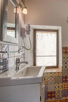 a bathroom with a sink and a window at Hôtel Restaurant Les Remparts in Venasque