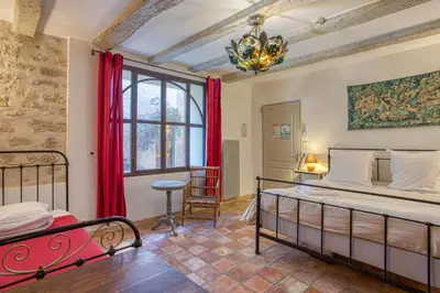 a bedroom with a bed and a chandelier at Hôtel Restaurant Les Remparts in Venasque