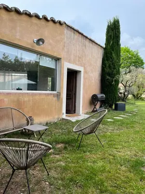 two chairs sitting in the grass in front of a building at Le p’tit bonheur-Piscine chauffée-clim-Park in Carpentras