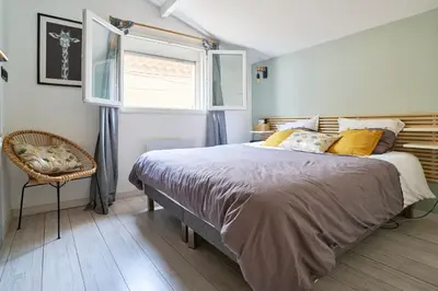 a bedroom with a bed and a window and a chair at Maison de ville moderne climatisée avec piscine in Morières-lès-Avignon