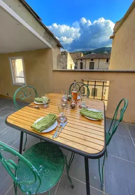 a wooden table and chairs on a patio at Le Petit Delphia in Apt