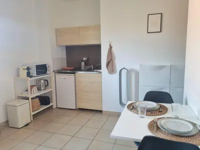 a kitchen with a table with chairs and a refrigerator at Joli studio lumineux centre avec parking securise dans quartier recherche in Aix-en-Provence